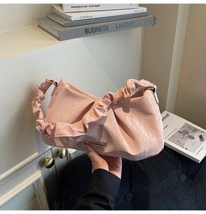 Detailed view of pale pink pleated handbag featuring soft ruched faux leather texture