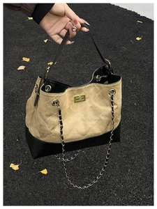 Detail of quilted leather bucket bag with contrasting stitching and golden metal clasp