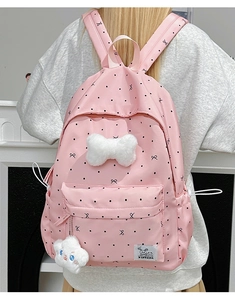 Detailed back view of pink polka dot backpack with plush bow and cloud charm on a model