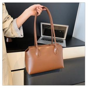 Close-up of caramel brown tote bag showing smooth PU leather texture in office setting