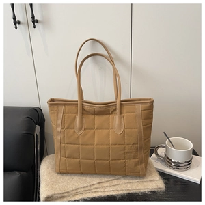 Detailed view of camel quilted tote bag in a cozy home setting with coffee and magazine
