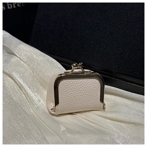 Macro view of cream litchi texture leather and gold metal clasp on a vintage mini bag