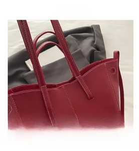 Detail of red lychee textured leather tote bag with white contrast stitching accents
