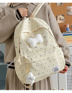 Close-up of beige polka dot backpack featuring a fluffy bow and cute cloud pendant charm