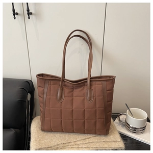 Detail of brown quilted tote bag showing rhombus stitching texture and leather handles