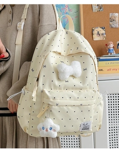 Close-up of beige polka dot backpack featuring a plush white bow and star charm detail