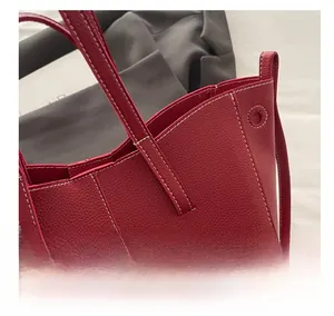 Close-up of wine red lychee grain leather tote bag with white contrast stitching details