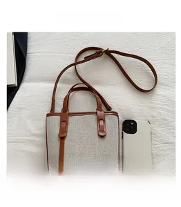 Close-up of canvas and brown leather bucket bag with a phone for size reference