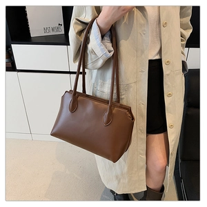 Brown leather tote bag worn by model in beige trench coat for a stylish commute look
