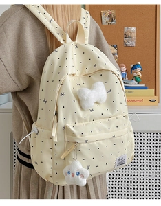 Detailed view of polka dot backpack featuring a plush star charm and front bow accent