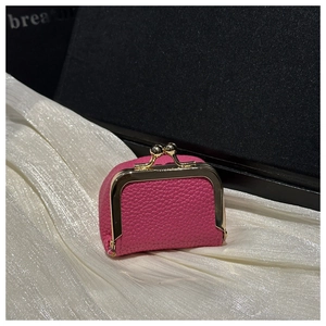 Close-up of rose red lychee leather coin purse with vintage gold metal clasp on silk