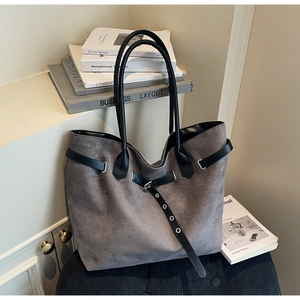 Detailed view of grey suede tote bag with black leather straps and silver metal eyelets