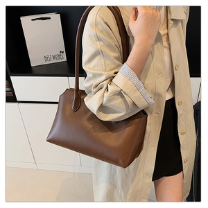 Close-up of a minimalist brown tote bag in matte synthetic leather with slim shoulder straps