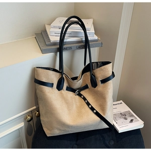 Close-up of khaki suede tote bag featuring black leather straps and metal eyelet details