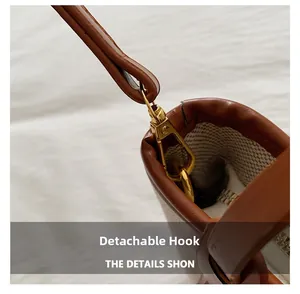 Detail of the detachable golden metal hook and brown faux leather trim on canvas bucket bag