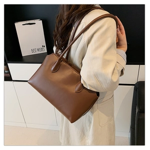 Brown leather tote bag worn over the shoulder by a model for a professional business look