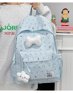 Close-up of light blue polka dot backpack with plush white bow and soft cloud charm