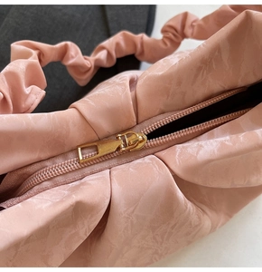 Close-up of the golden metal zipper and soft pleated texture on this pink shoulder bag