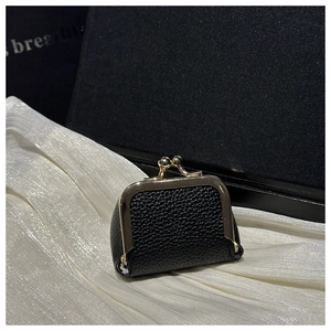 Detail of black lychee grain leather coin purse with golden kiss-lock closure