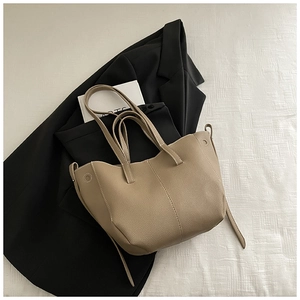 Close-up of beige lychee texture bucket bag with contrast stitching on black blazer