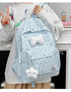 Detail of light blue polka dot backpack with plush bone and star charms on model