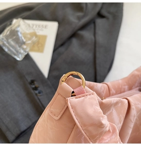 Detailed macro view of pink pleated fabric bag with gold metal buckle and nylon strap