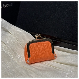 Detailed view of mini orange leather kiss-lock jewelry pouch on white silk fabric