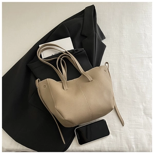 Detail of minimalist beige pebbled leather bucket bag with long strap and spacious interior