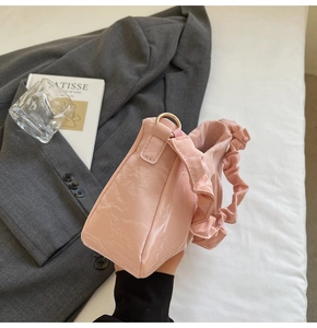Detail of pink pleated handbag featuring shiny synthetic leather and gold metal ring hardware