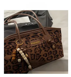 Detail of leopard print suede tote bag with leather label and wooden bead tassel