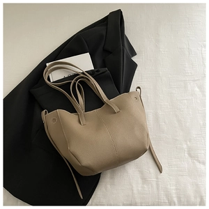 Detail of khaki leather bucket bag with white contrast stitching and long shoulder straps