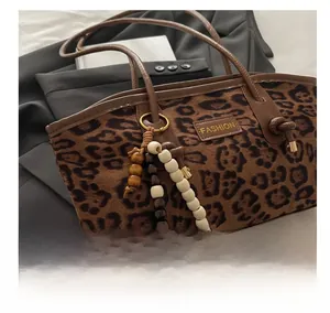 Close-up of leopard print suede tote with fashion logo and beaded tassel detail