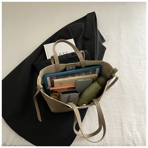 Top view of spacious beige leather tote bag interior with tablet and daily essentials