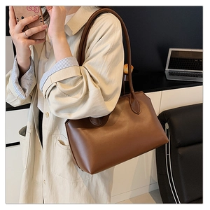 Detail of a dark brown leather tote bag on a desk in a modern minimalist office