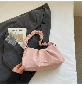 Close-up of pink pleated shoulder bag with marble texture and silver logo badge