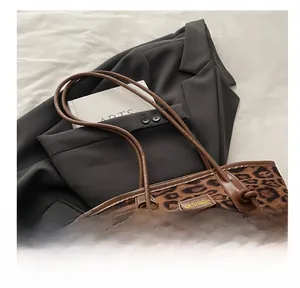 Detail of leopard print suede tote bag with leather strap and wooden bead charm accessory