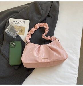 Detail of pink pleated hobo bag with a scrunchie handle and metallic logo on soft leather