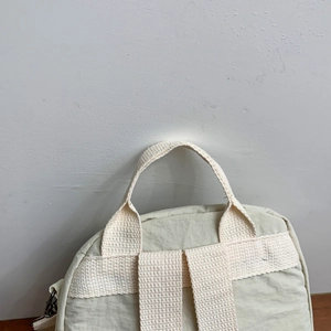 Off-white nylon backpack with wide handles and reinforced shoulder straps for travel