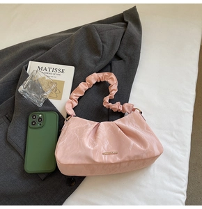 Detail of pink ruched shoulder bag with marble texture and golden logo plaque