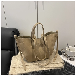 Detail of minimalist apricot leather tote bag with lychee texture and side metal eyelets