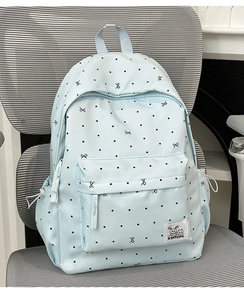Close-up of light blue polka dot backpack showing front pocket and ribbon patterns