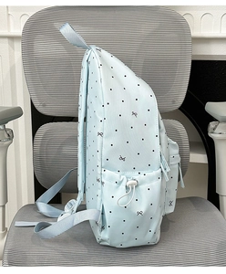 Side view of light blue polka dot backpack showing side pocket and drawstring detail