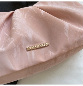 Close-up of pink marble pattern leather with pleated texture and golden metal logo