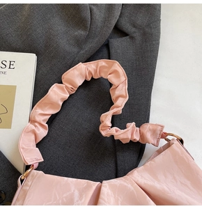 Detail of light pink ruched handbag strap with metallic rings on a grey blazer