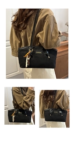 Detail of black suede tote bag with golden fashion tag and colorful beaded tassel charm