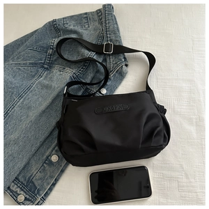 Macro shot of black nylon crossbody bag with pleated texture and adjustable strap