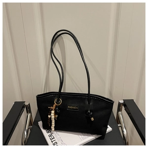 Detail of minimalist black tote bag with fashion tag and colorful bead pendant on chair