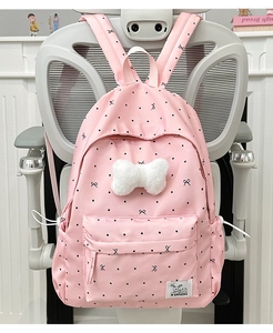 Detail of pink backpack with black dots and a large white plush bow on a chair