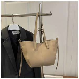 Macro detail of beige lychee textured leather tote bag with reinforced double handles