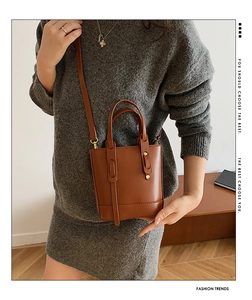 Detail view of brown PU leather bucket bag featuring gold hardware and long shoulder strap